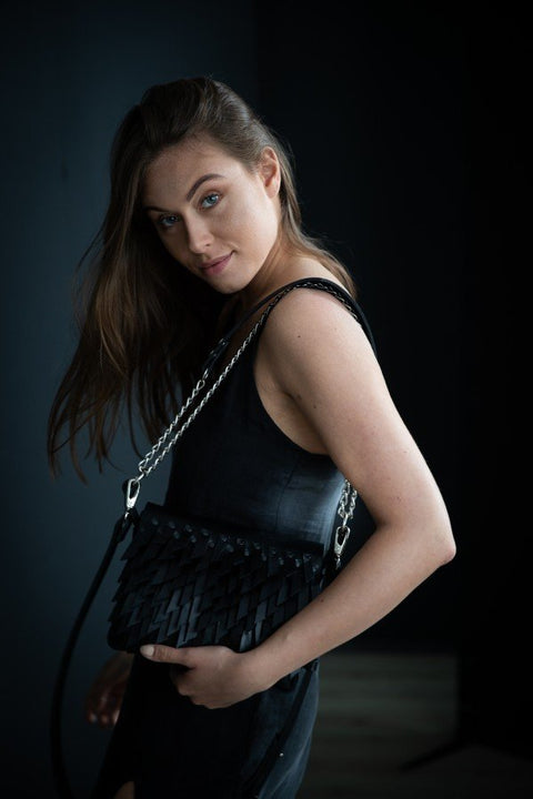 1. Woman wearing black dress holding PYKOK BARBED SISTER handbag with chain strap in dark setting