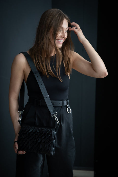 2. Smiling woman in black outfit with PYKOK BARBED SISTER handbag featuring leather strap