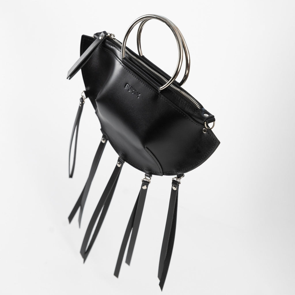 11. Black leather KAYA handbag with metal ring handles and tassels, shown at an angle against a white background