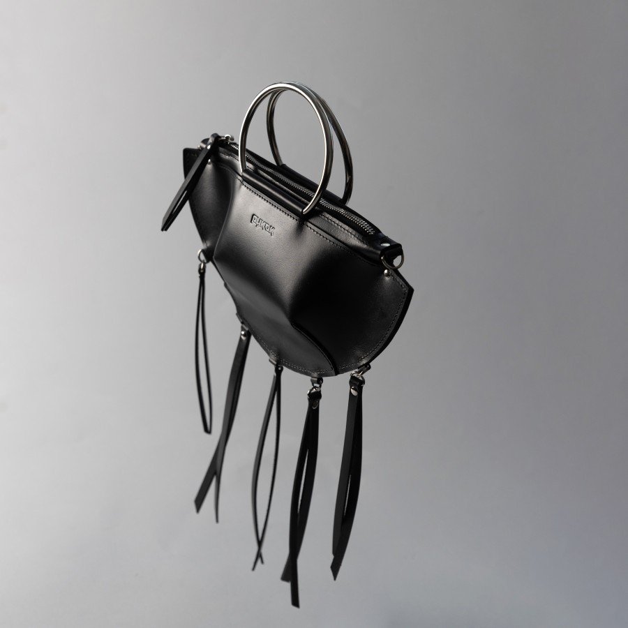 2. Black leather KAYA handbag with metal ring handles and tassels, shown at an angle against a grey background