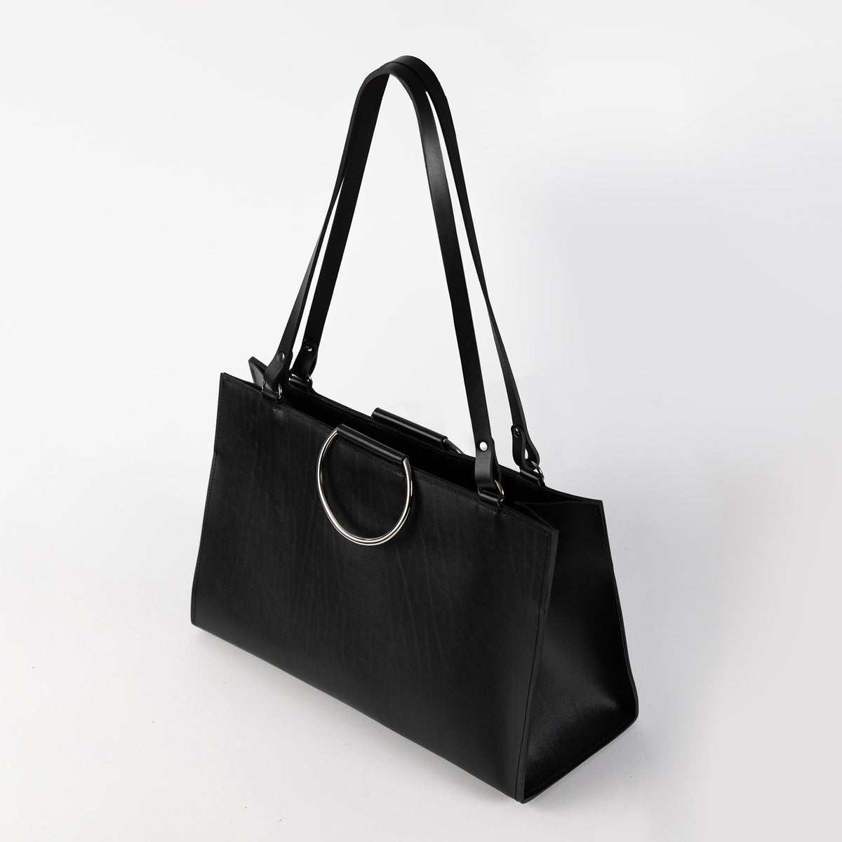 1. Black structured leather handbag with metal ring handles and long shoulder straps, shown in studio setting
