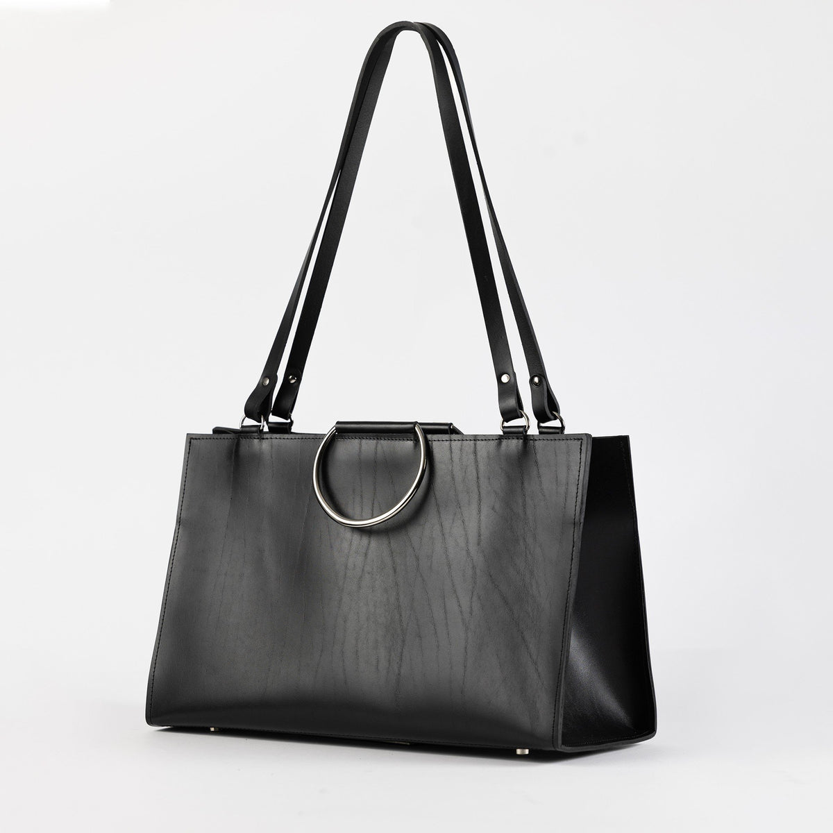 3. Black leather handbag with metal ring handles and long straps, shown in a studio environment