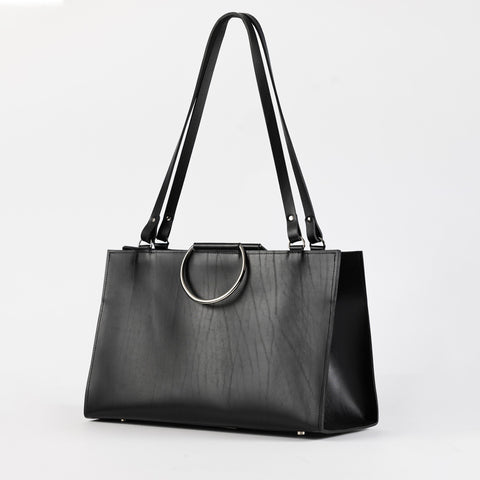 3. Black leather handbag with metal ring handles and long straps, shown in a studio environment