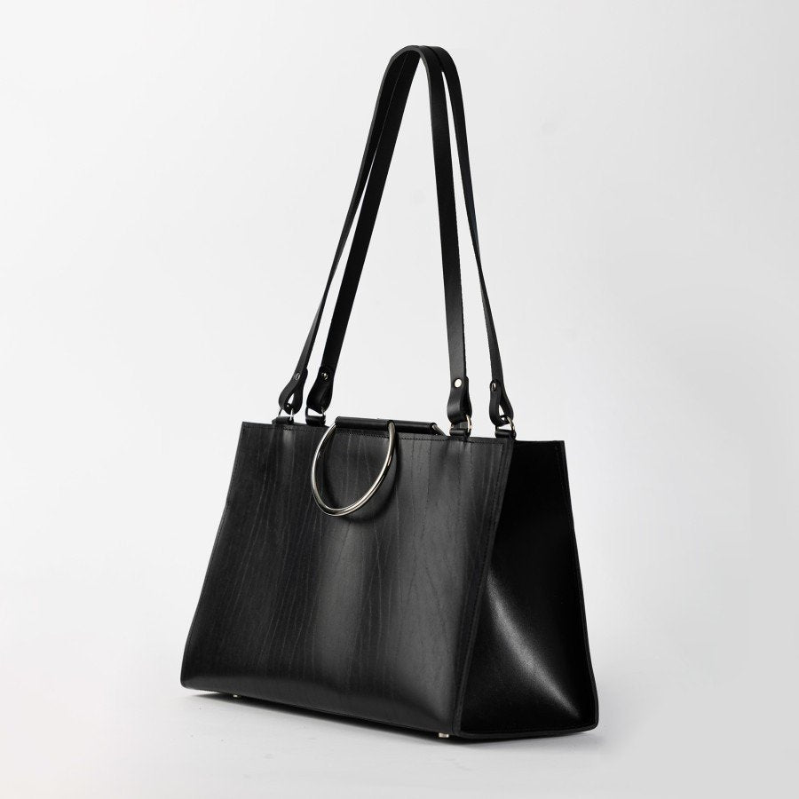 2. Black leather handbag with metal ring handles and shoulder straps, displayed in studio lighting