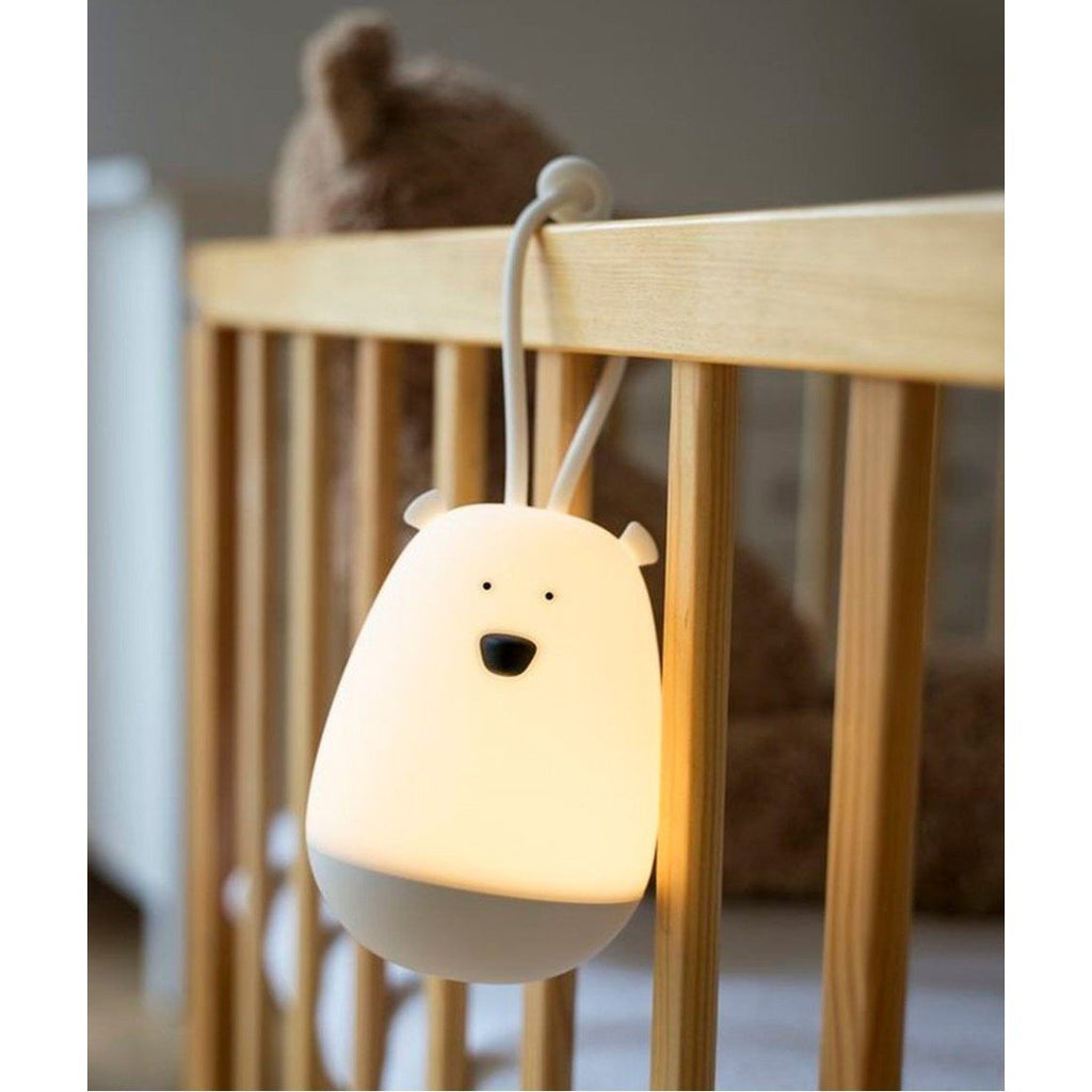 3. Illuminated white bear-shaped night light hanging on a wooden crib with a teddy bear in the background
