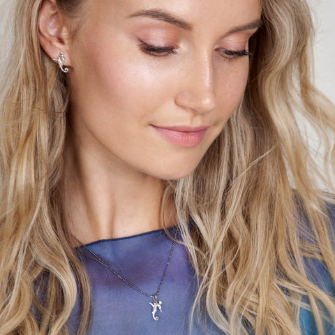 1. Woman wearing Tanel Veenre rose gold seahorse pendant and matching earrings, smiling softly