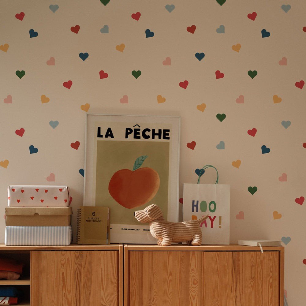 1. Children's room with colorful heart-patterned wallpaper by Dekornik, featuring a wooden cabinet, framed art, and toys on top