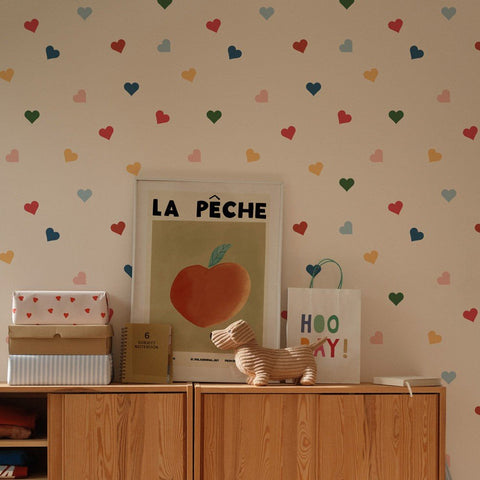 1. Children's room with colorful heart-patterned wallpaper by Dekornik, featuring a wooden cabinet, framed art, and toys on top