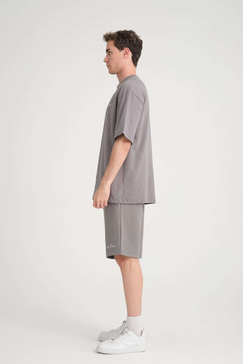 3. Side profile of man in grey oversized t-shirt and matching shorts with white sneakers