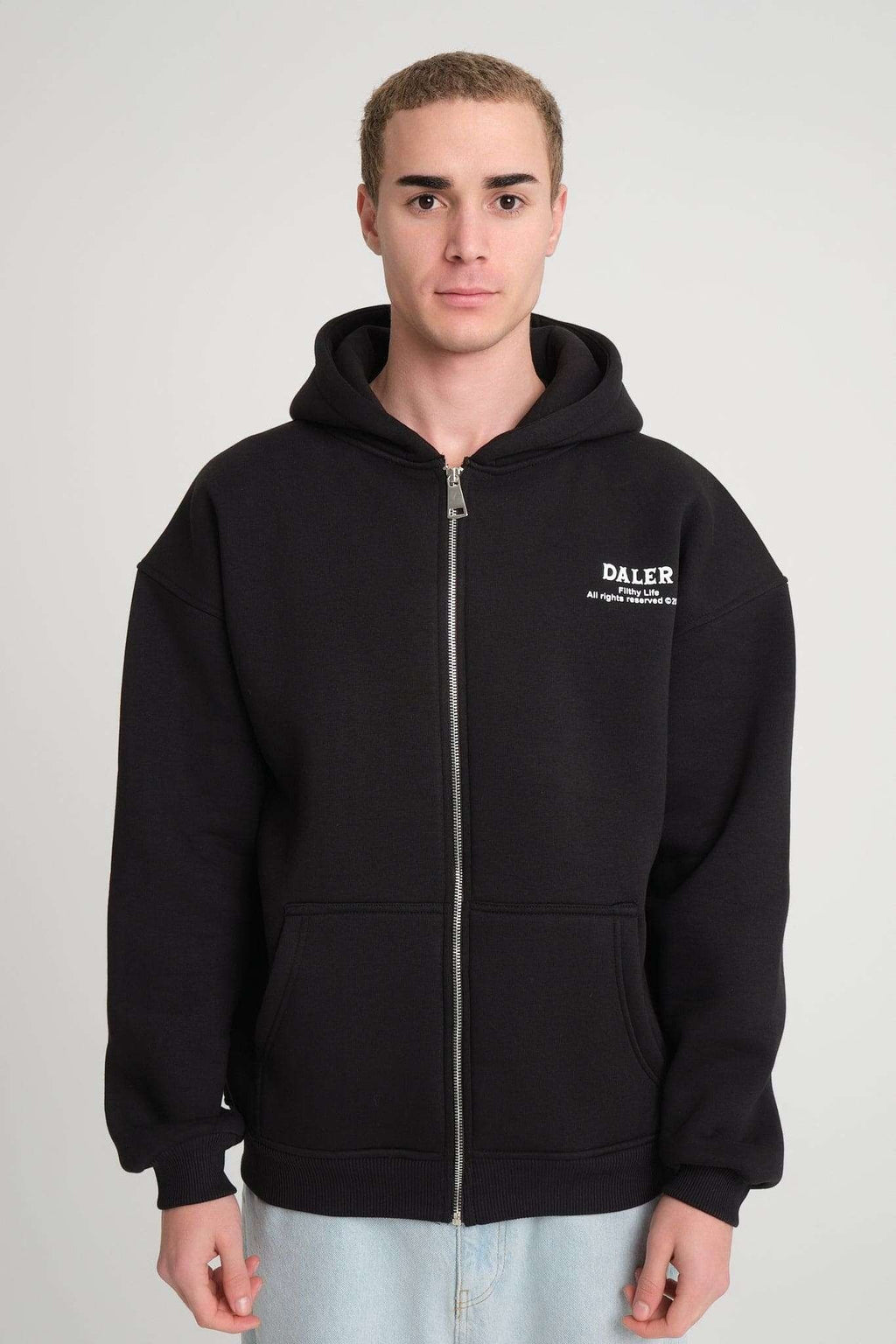 4. Front view of man wearing black DalerClo hoodie with zipper and logo, showcasing the relaxed fit and practical pockets.