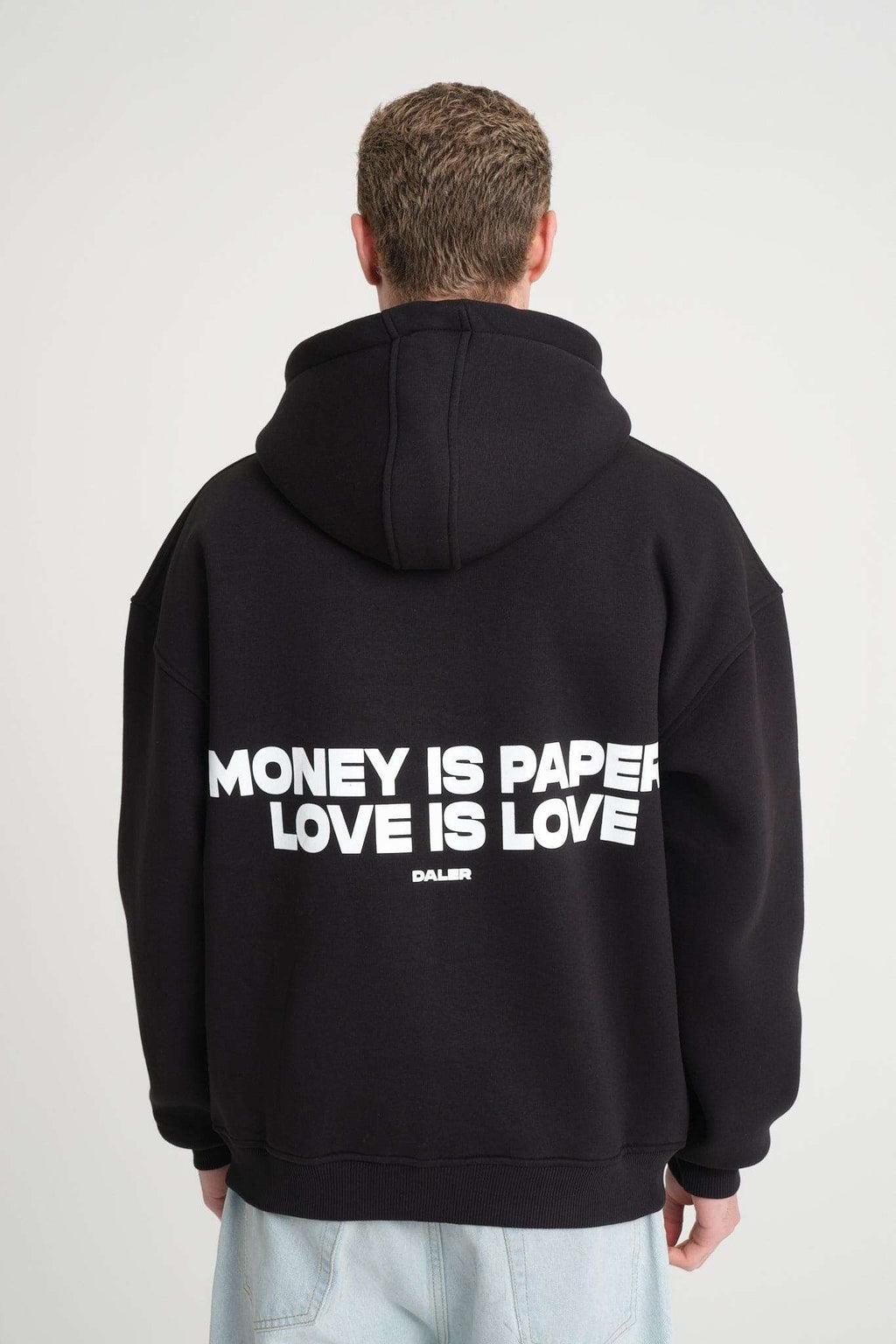 3. Back view of black hoodie with 'Money is Paper, Love is Love' text, worn by a man, highlighting the oversized fit and hood.