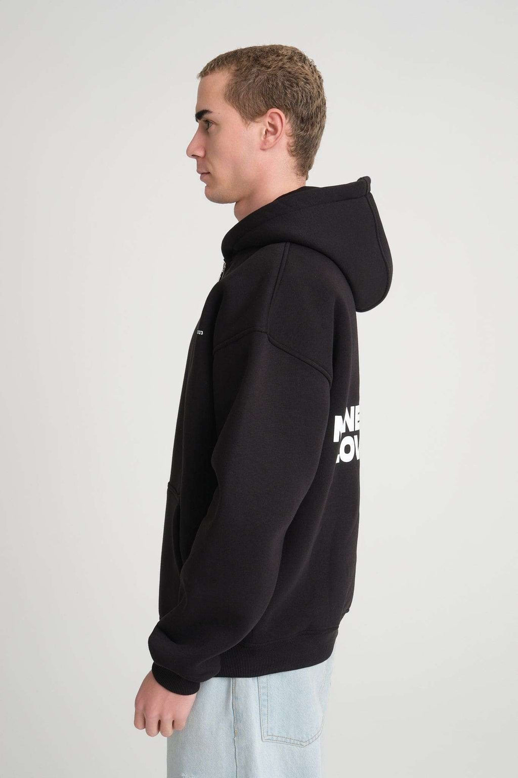 7. Side view of man wearing black hoodie with visible text on back, showcasing the oversized fit and hood.