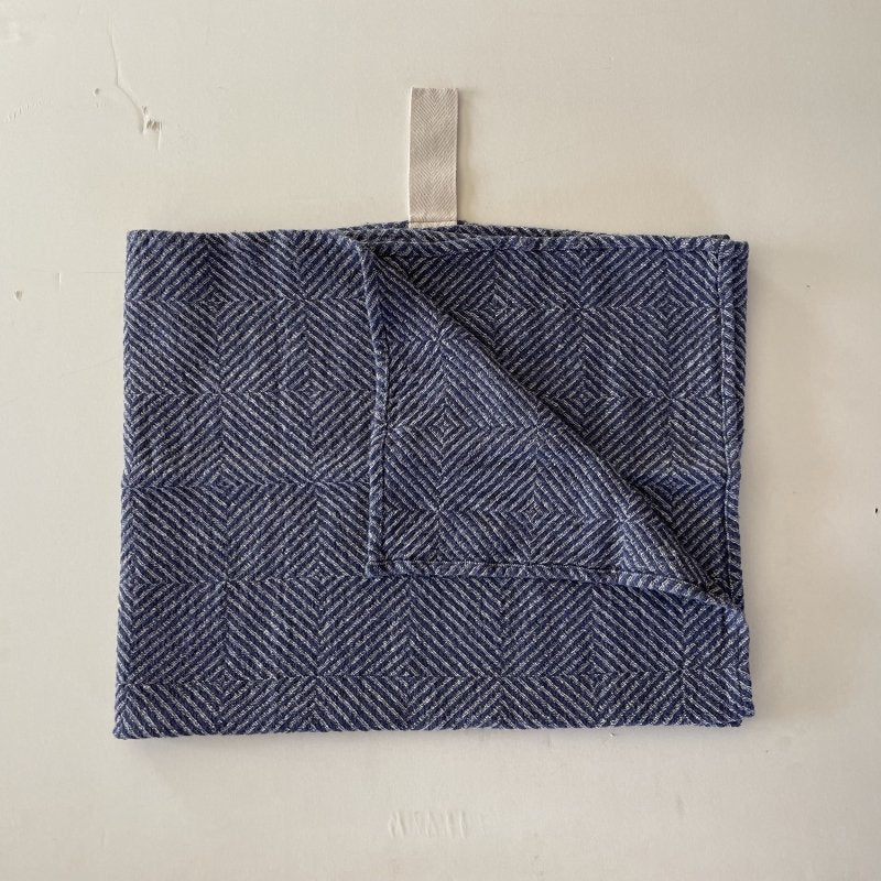 4. Flat lay of blue fishbone pattern linen towel with white cotton hanger, corner folded