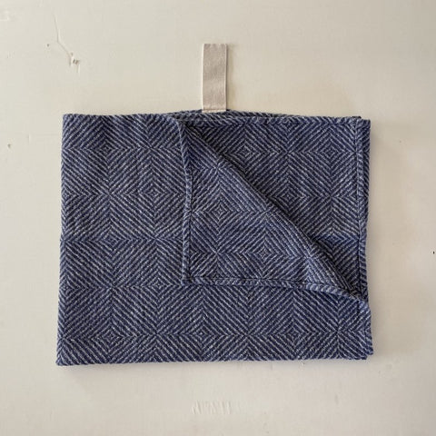4. Flat lay of blue fishbone pattern linen towel with white cotton hanger, corner folded