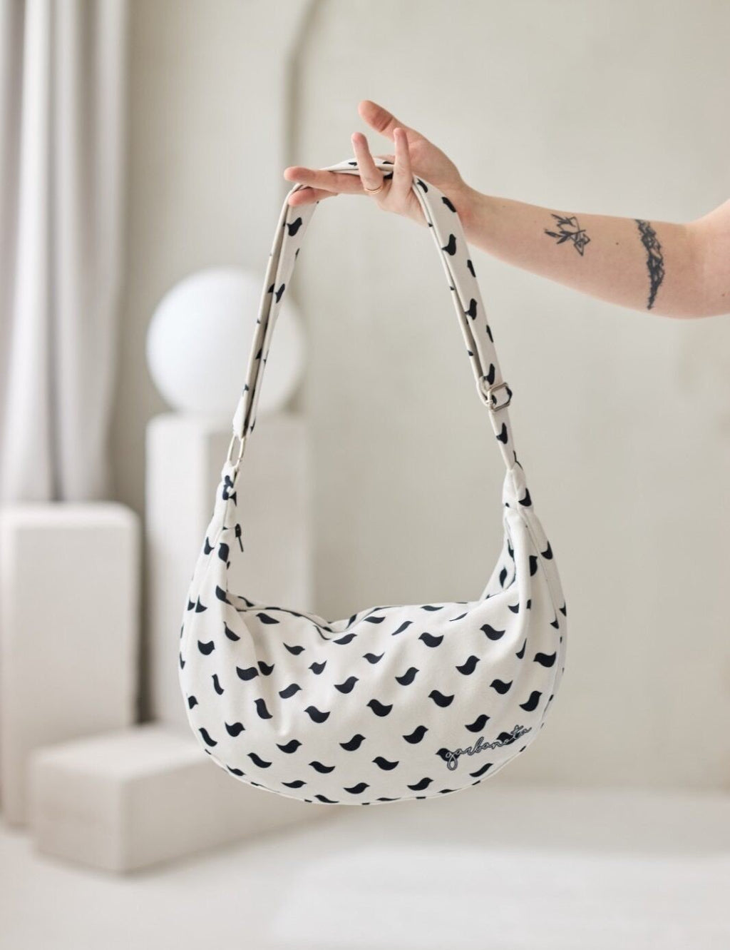 4. Studio shot of Garbanota Hobo Bag Birds in white with black bird pattern, showing adjustable strap