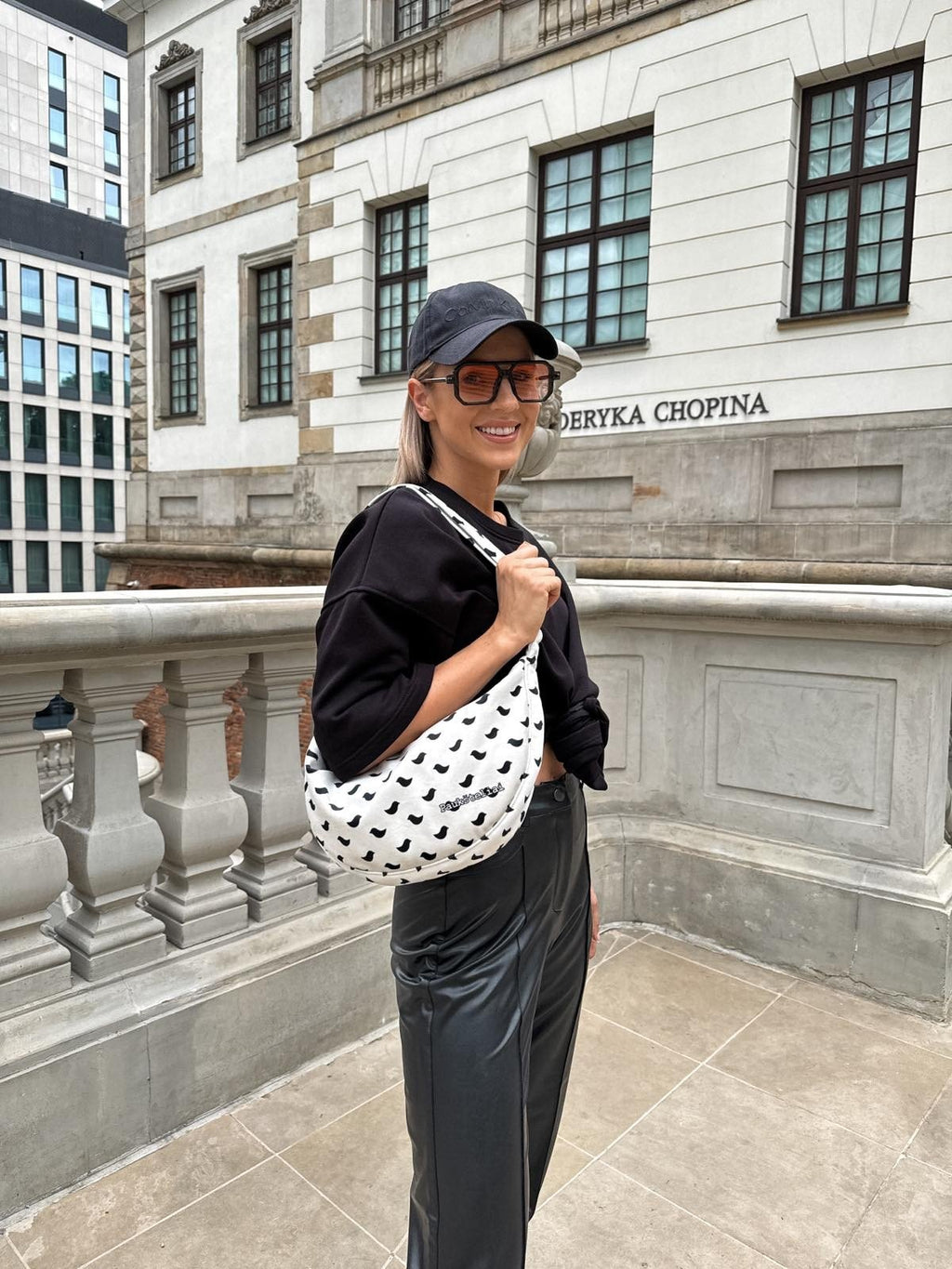 2. Woman holding Garbanota Hobo Bag Birds in white with black bird pattern, styled with casual outfit outdoors