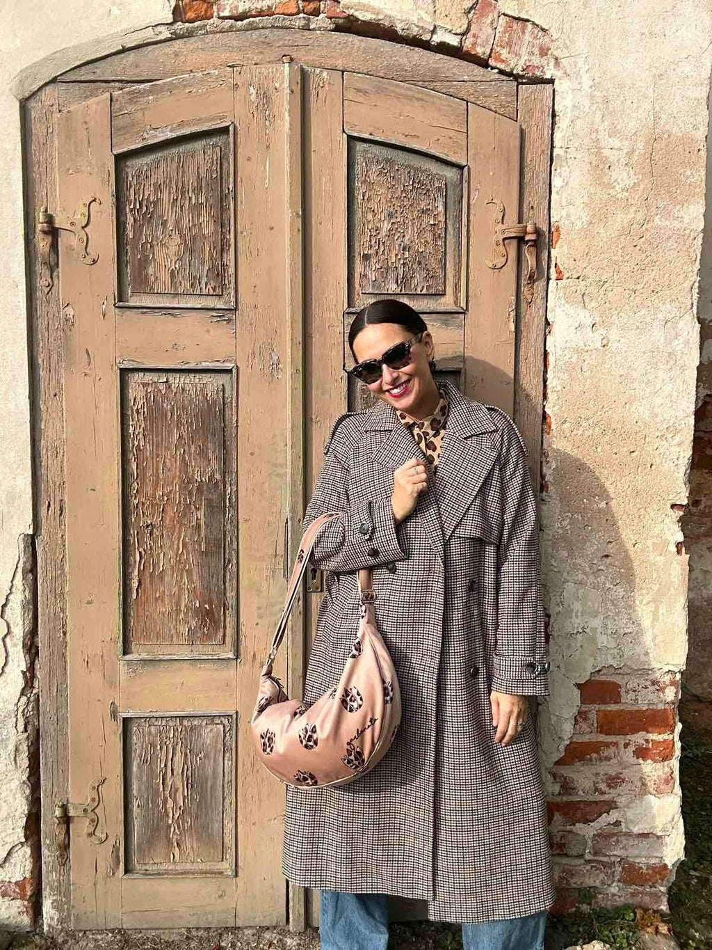 2. Woman showcasing Garbanota Hobo Bag in Brown Leopard Tulips, styled with a coat, standing outdoors