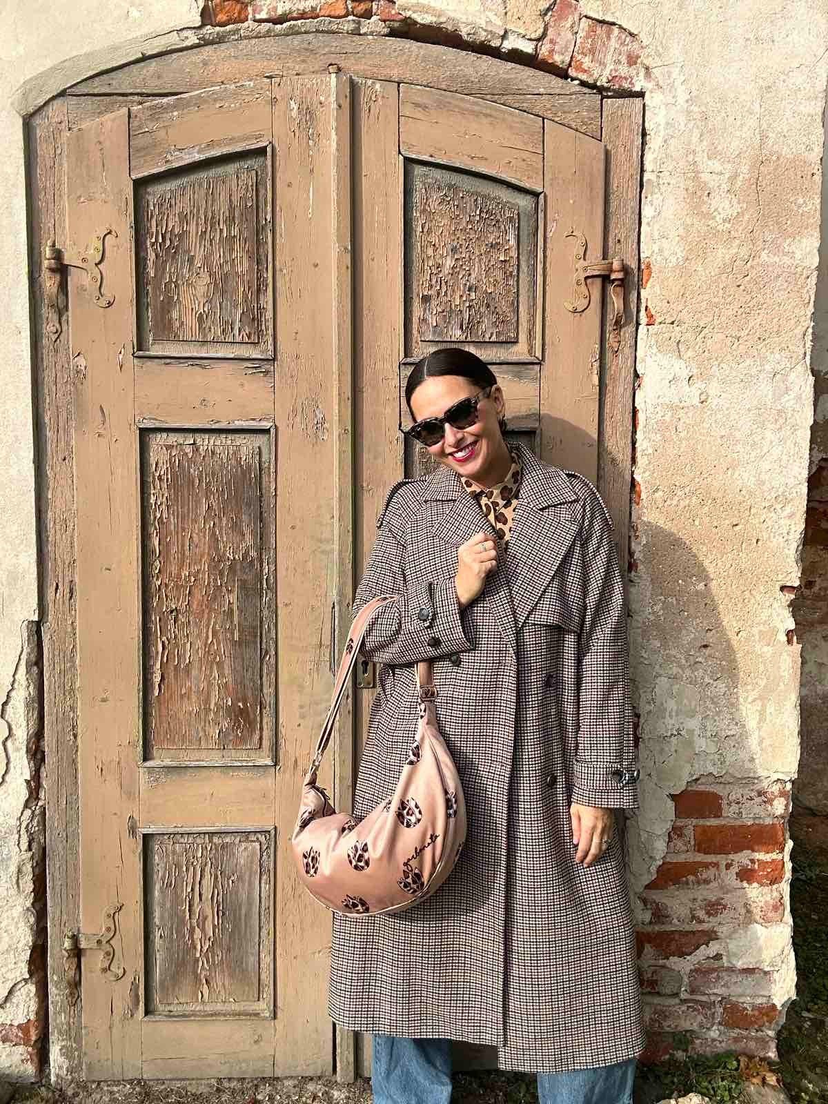 2. Woman showcasing Garbanota Hobo Bag in Brown Leopard Tulips, styled with a coat, standing outdoors