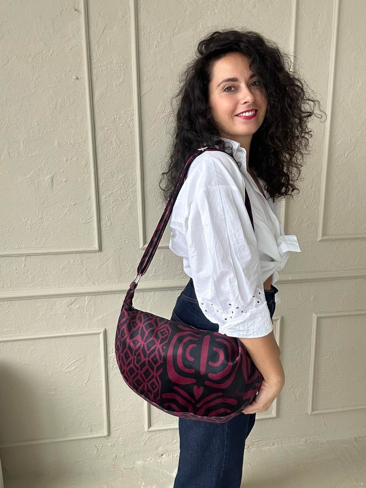 1. Woman wearing Garbanota burgundy pattern hobo bag with adjustable strap, styled with white blouse and jeans