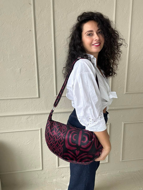 1. Woman wearing Garbanota burgundy pattern hobo bag with adjustable strap, styled with white blouse and jeans
