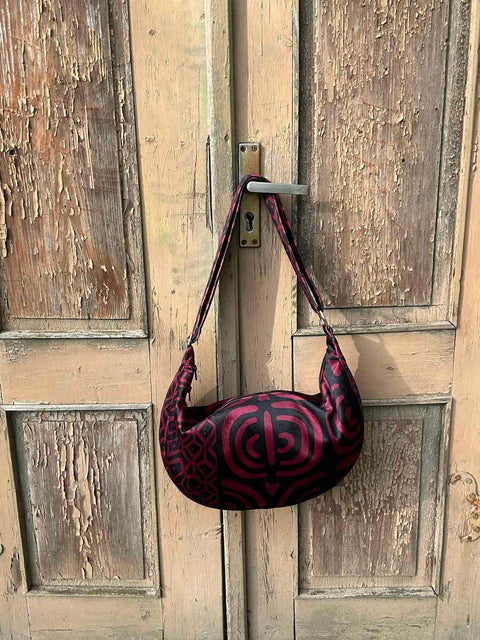2. Garbanota burgundy pattern hobo bag hanging on rustic wooden door, showcasing unique design and soft velour material
