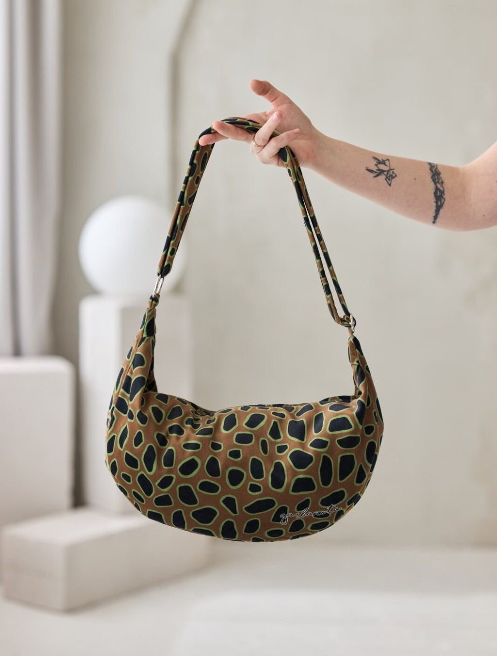 2. Garbanota Curly Leopard Hobo Bag held in studio, highlighting soft velour material and unique pattern