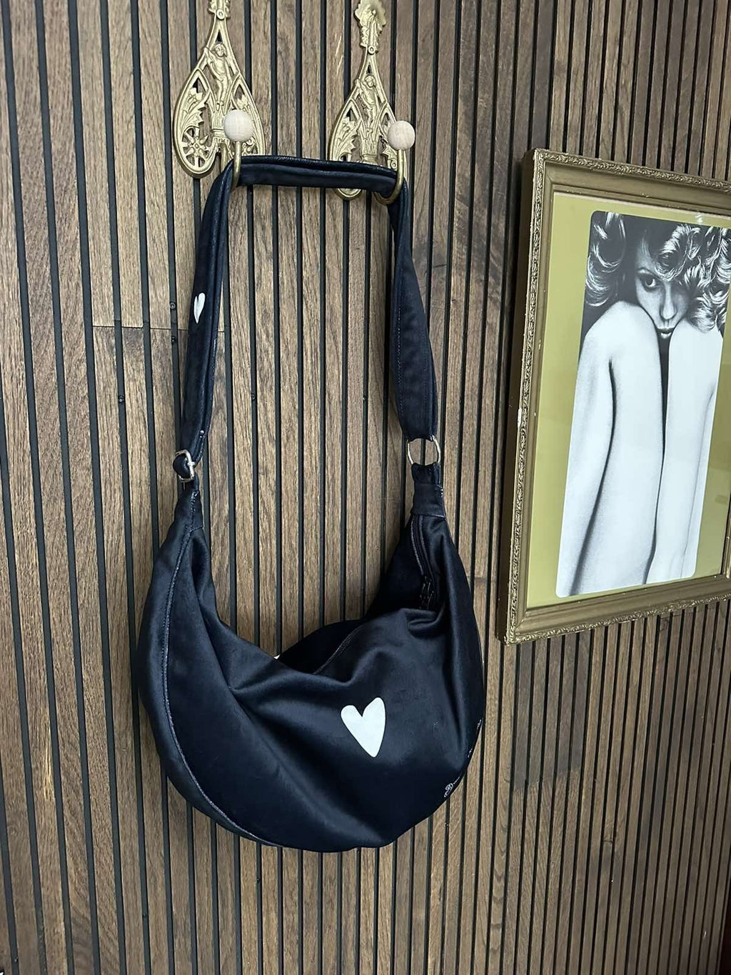 4. Woman displaying Garbanota Hobo Bag Heart in black with heart detail, worn crossbody indoors
