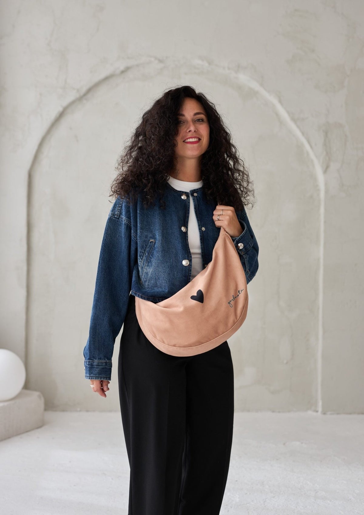1. Woman wearing Garbanota Hobo Bag Heart in cream, styled with denim jacket, lifestyle setting