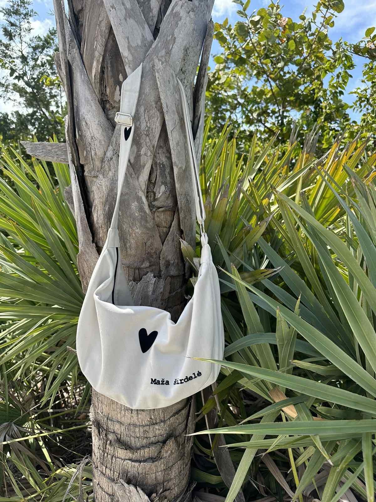 11. Garbanota Hobo Bag Heart in white hanging on tree, showcasing heart detail and craftsmanship