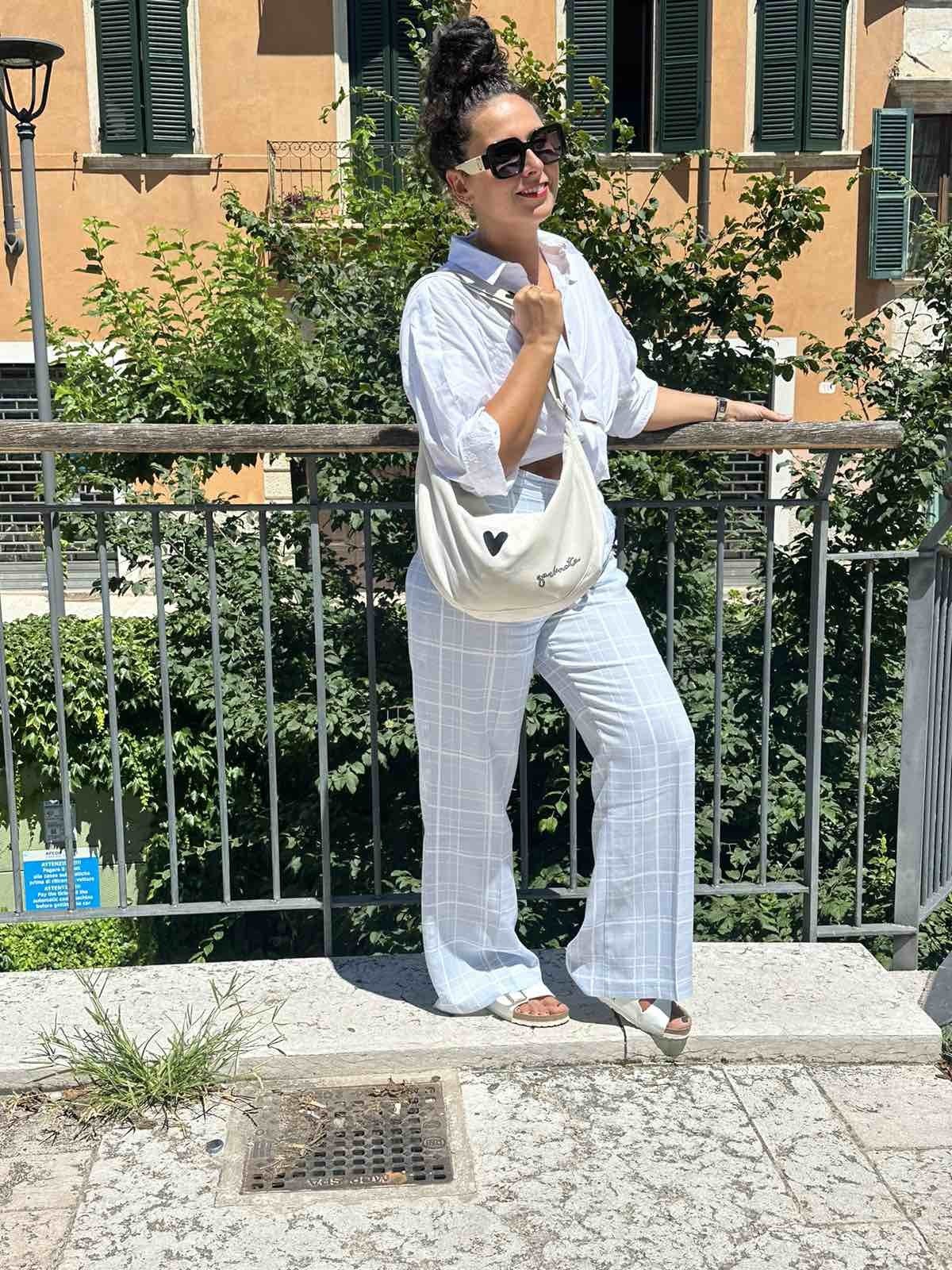5. Woman posing on street with Garbanota Hobo Bag Heart in white, wearing casual white outfit