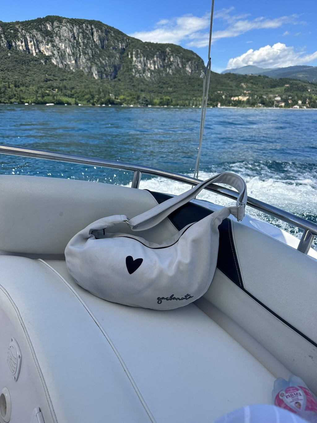 6. Garbanota Hobo Bag Heart in white placed on boat seat, showing heart detail and adjustable strap