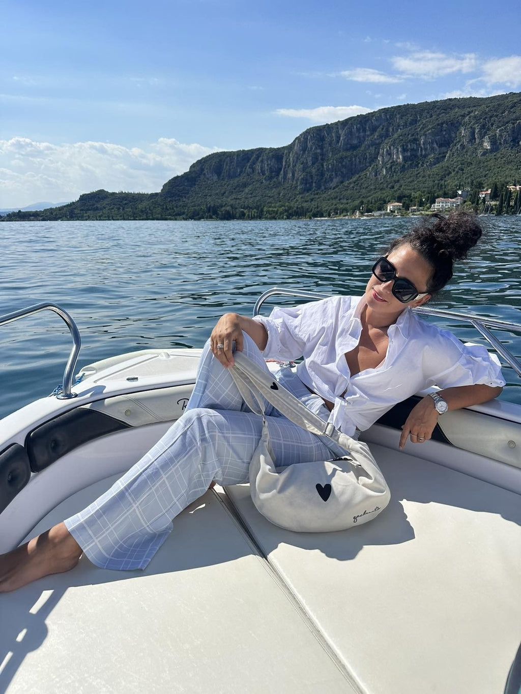 4. Woman relaxing on boat with Garbanota Hobo Bag Heart in white, enjoying sunny day