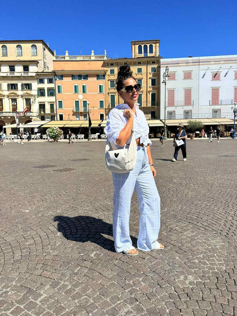 2. Woman in city square wearing Garbanota Hobo Bag Heart in white, styled with casual denim outfit
