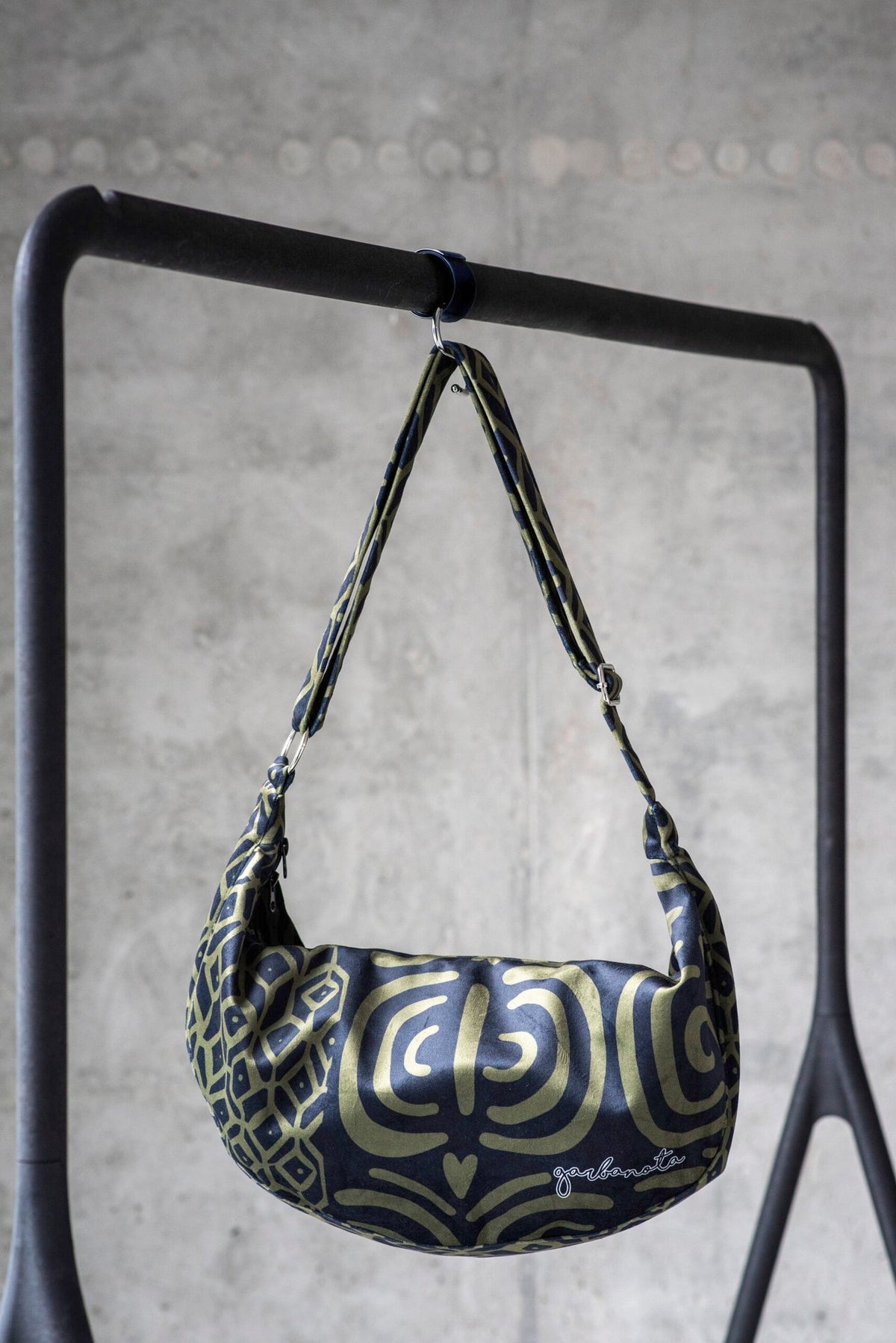 3. Garbanota Hobo Bag in khaki pattern hanging on a stand, emphasizing the unique design and adjustable strap