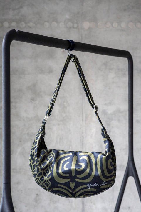 3. Garbanota Hobo Bag in khaki pattern hanging on a stand, emphasizing the unique design and adjustable strap