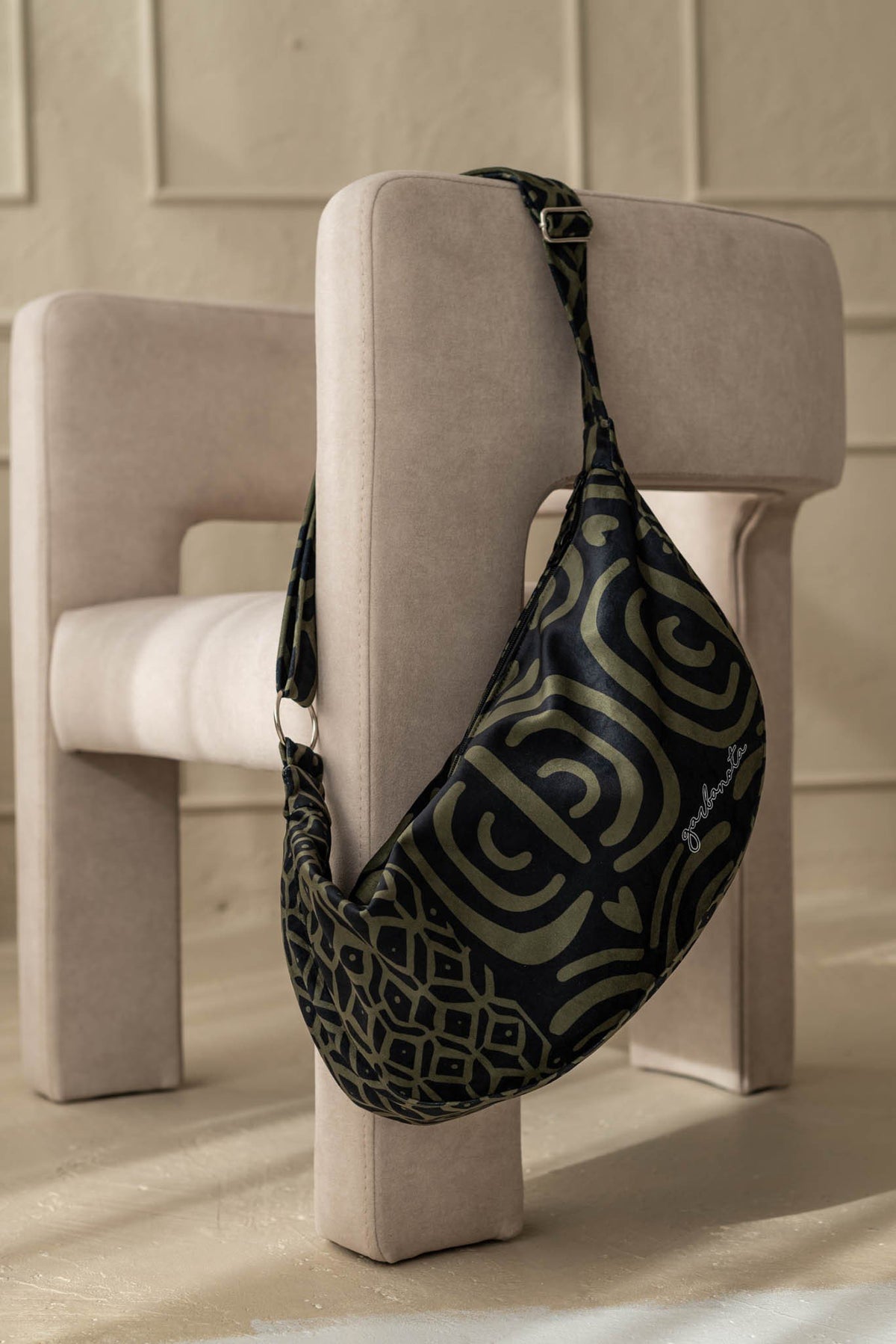 1. Garbanota Hobo Bag in khaki pattern displayed on a modern chair, showcasing its soft velour exterior and adjustable strap