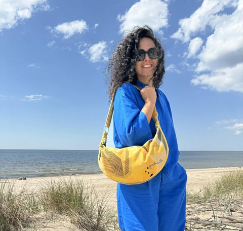 1. Woman wearing Garbanota Hobo Bag in Lemon on a beach, showcasing adjustable strap and velour exterior
