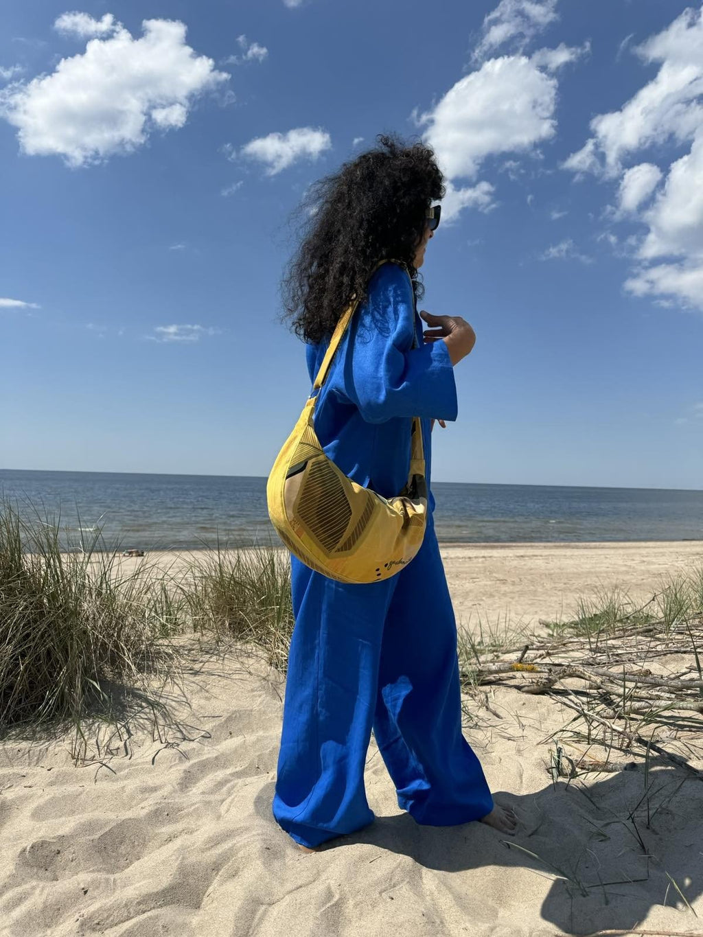2. Woman with Garbanota Hobo Bag in Lemon, side view on a beach, highlighting suede-like velour material