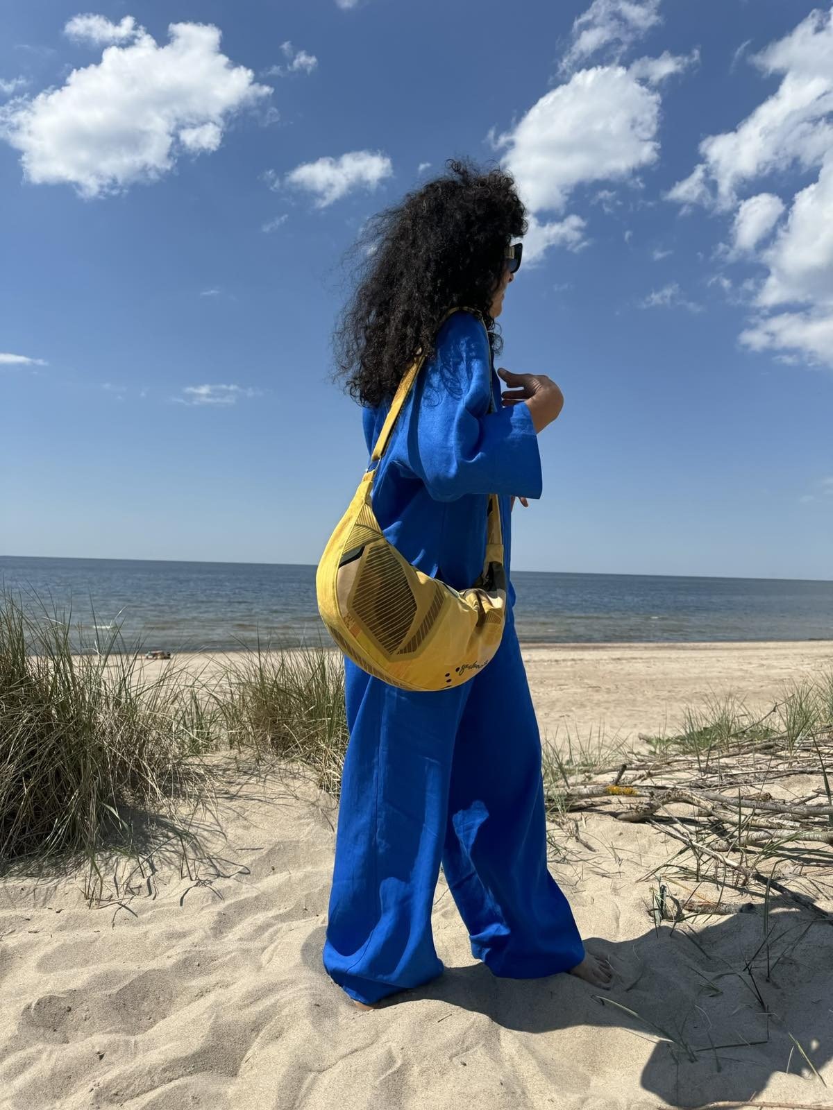 2. Woman with Garbanota Hobo Bag in Lemon, side view on a beach, highlighting suede-like velour material