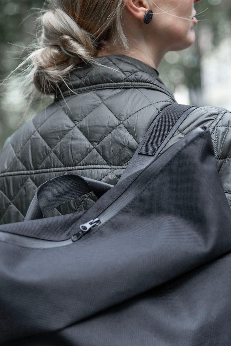 7. Close-up of Nordhale HØLAR Weatherproof Backpack on female model, highlighting water-repellent polyester material