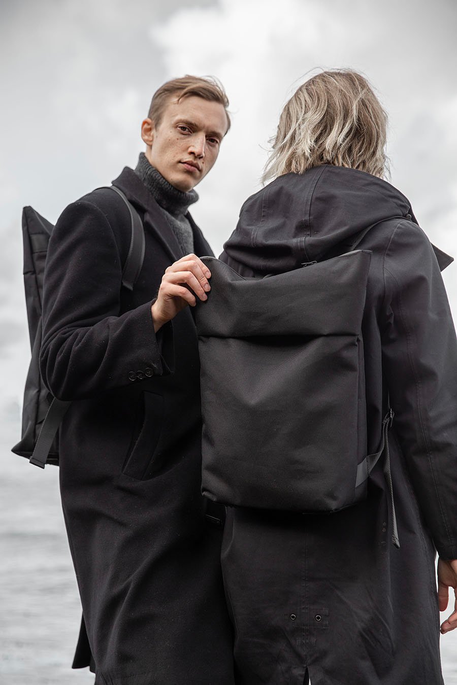 4. Unisex Nordhale HØLAR Weatherproof Backpack worn by male and female models, close-up of minimalist design in outdoor setting