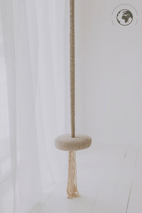 1. Children's bouclé pearl white swing with cotton rope hanging in a minimalistic white room