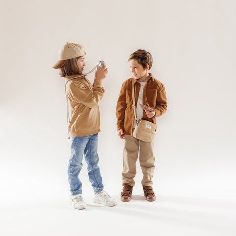 1. Two children standing, one taking a photo with Hoppstar Artist Memo camera, both wearing casual outfits