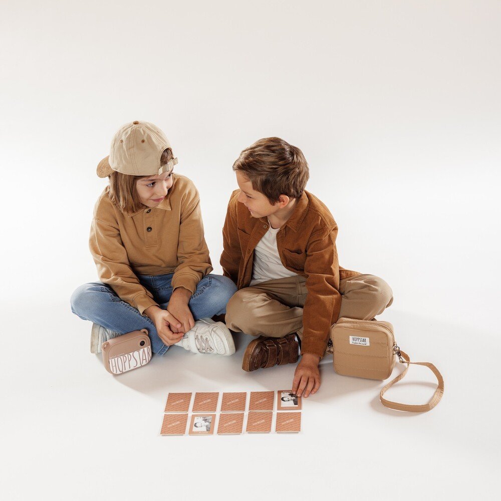1. Two children sitting on floor playing Hoppstar Memory Game with brown envelopes and camera
