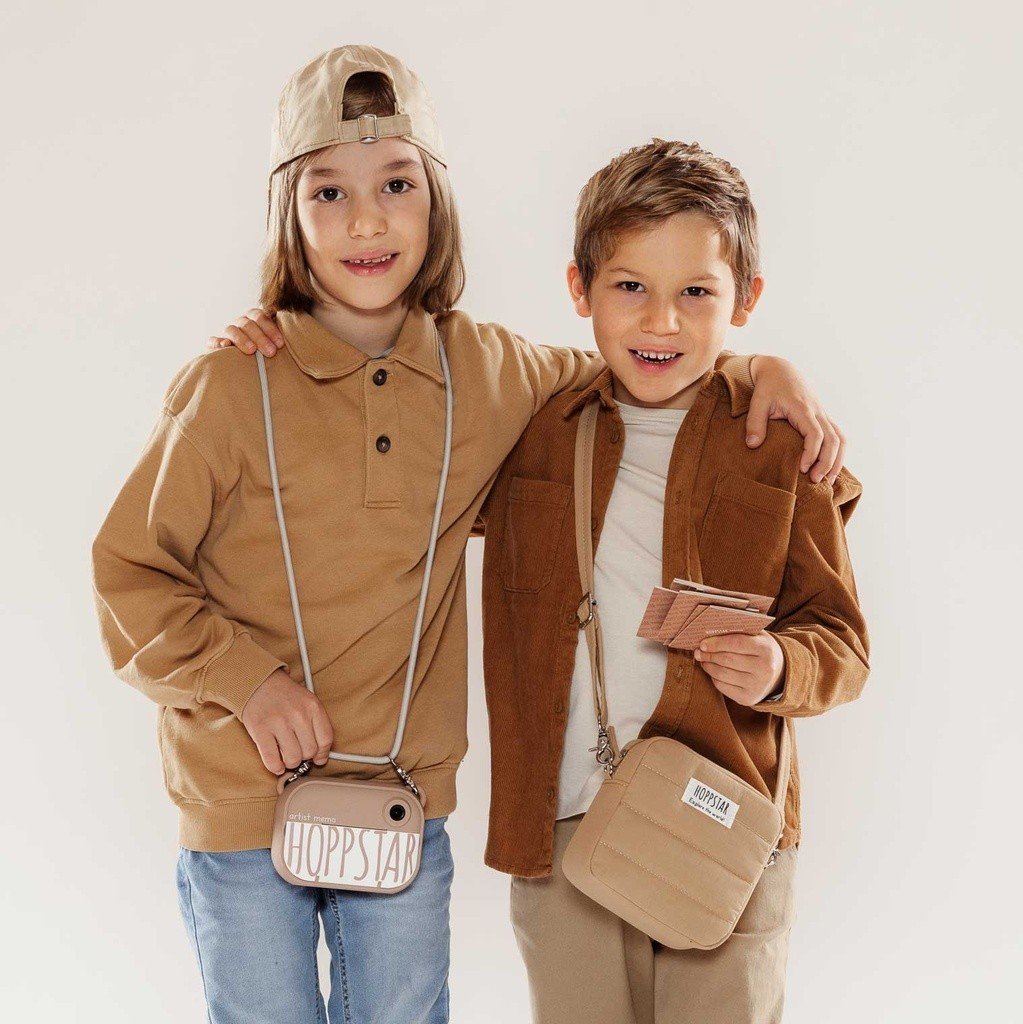 7. Two children wearing Hoppstar camera bags, one pink and one beige, in casual setting