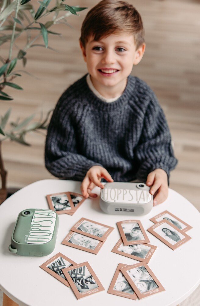 1. Boy smiling while playing Hoppstar Memory Game with personalized photo cards on a white table