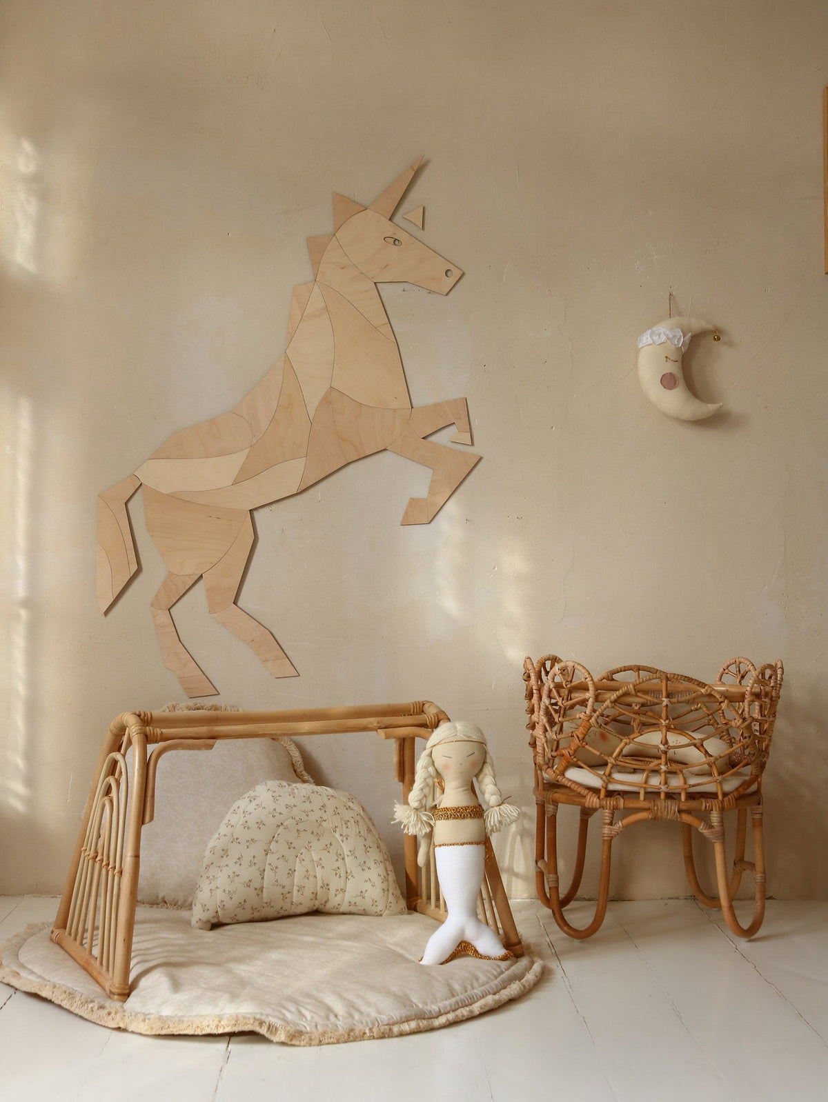 8. Wooden origami unicorn wall decoration in a nursery with rattan furniture and a moon wall hanging