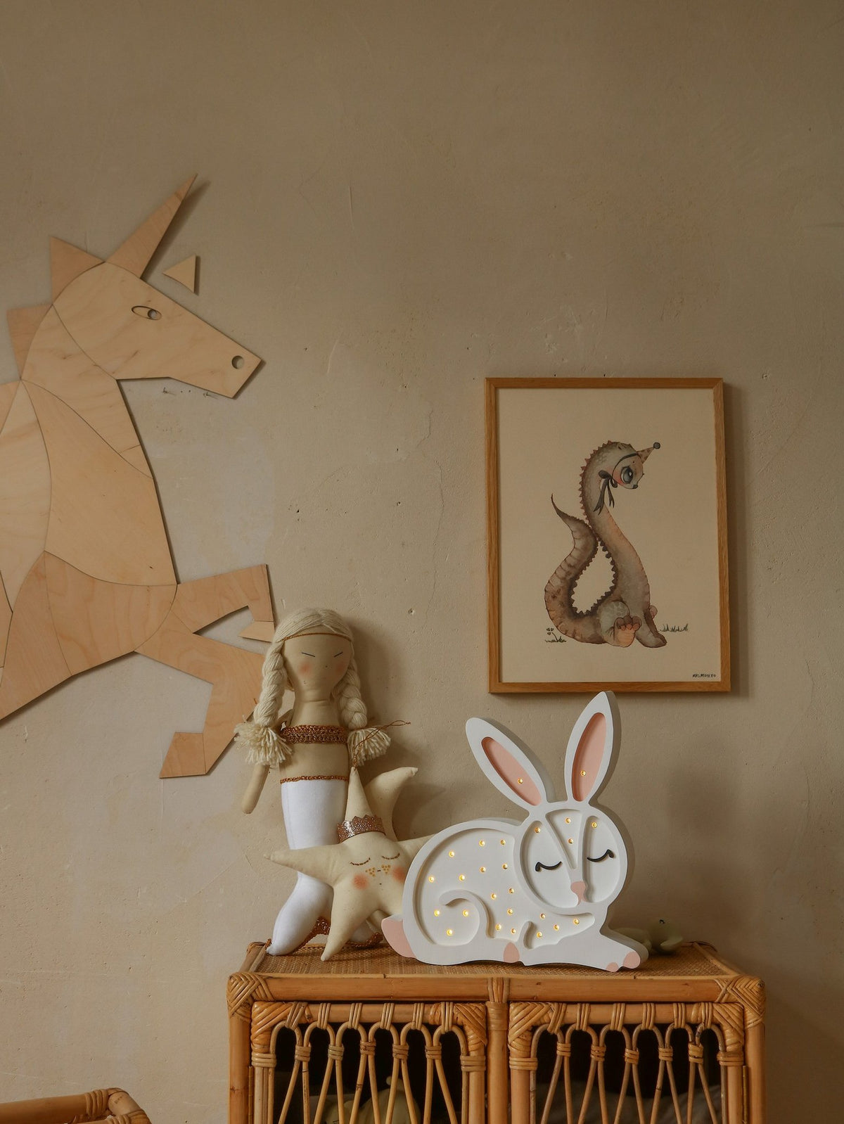 7. Close-up of wooden origami unicorn wall decoration next to a wicker cabinet with toys