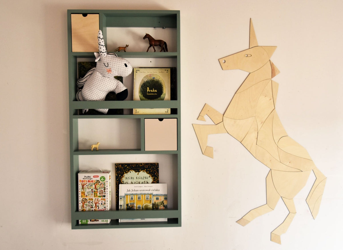 2. Wooden origami unicorn wall decoration next to a green shelf with books and toys