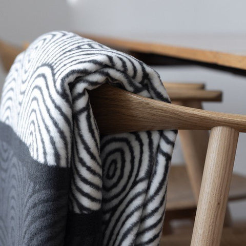 1. Gray and white Labbvenn pet blanket with round and linear patterns draped over a wooden chair in a modern interior setting